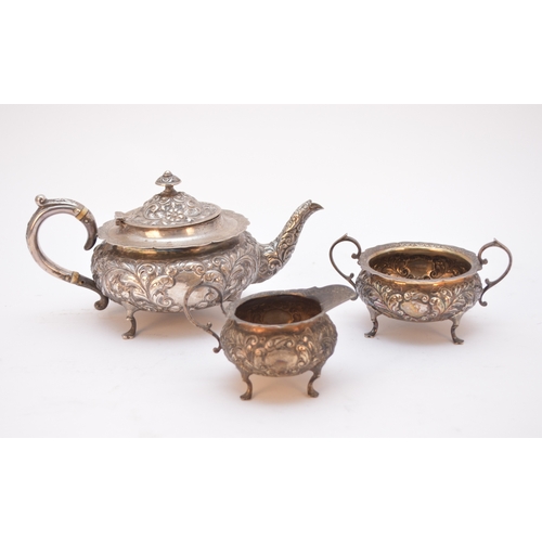 57 - A matched three piece silver tea service, each piece of circular form with embossed scroll decoratio... 