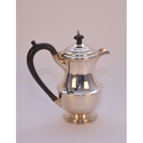 9 - A silver hot water jug, T S, Birmingham 1932, of baluster form with turned ebonised handle and finia... 