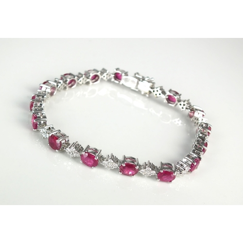 107 - An 18ct white gold ruby and diamond bracelet, designed as sixteen oval mixed cut rubies each intersp... 