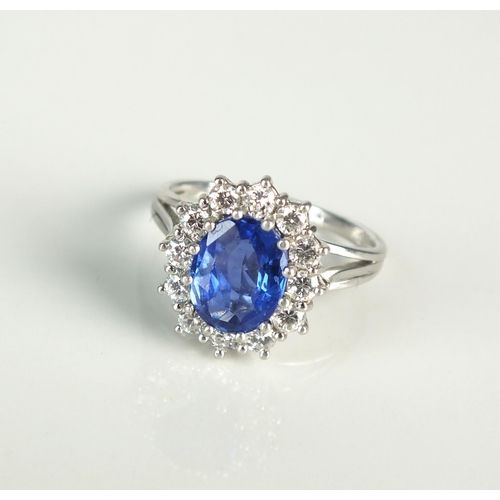 16 - An oval sapphire and diamond cluster ring, designed as a central oval mixed cut sapphire claw set wi... 