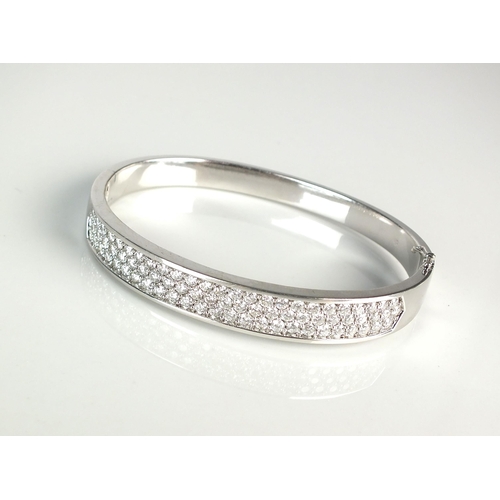 17 - An 18ct white gold diamond set bangle, designed as three rows of brilliant cut diamonds all claw set... 