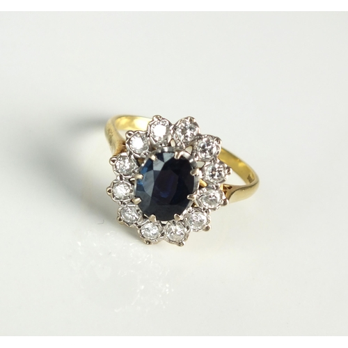 24 - An 18ct gold sapphire and diamond oval cluster ring, designed as a central oval mixed cut sapphire c... 