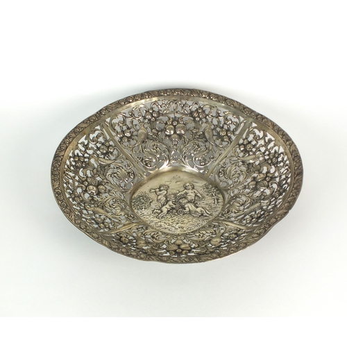 3 - A white metal decorative pierced bowl, the centre embossed with four cherubs amongst a landscape, al... 