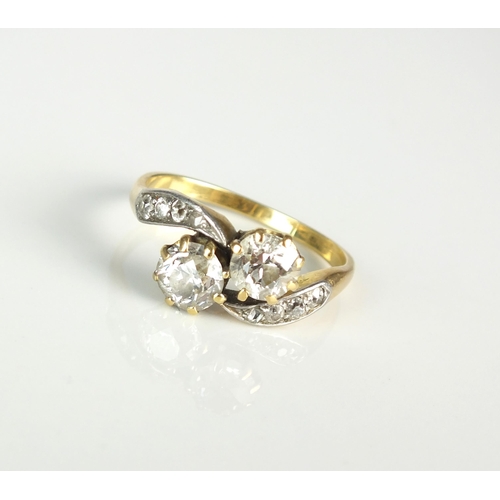 31 - A two stone diamond crossover ring, the two old cut diamonds claw set in yellow metal to tapering di... 