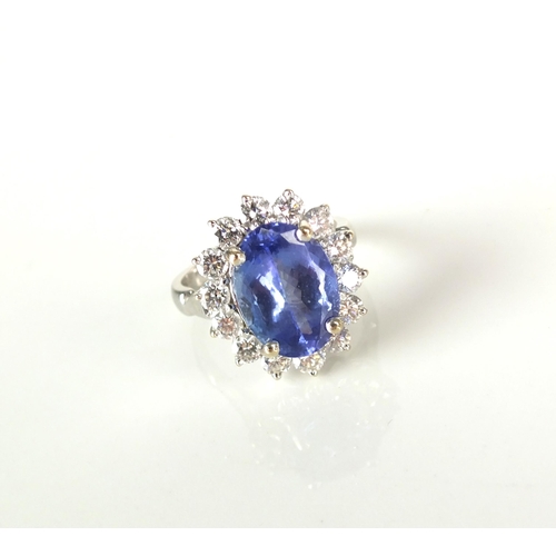 33 - A tanzanite and diamond oval cluster ring, designed as a central oval mixed cut tanzanite claw set i... 