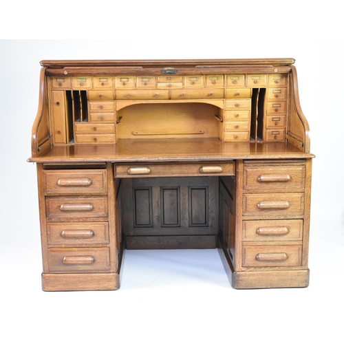 344 - A 20th century oak roll-top pedestal desk The top with tambour shutter enclosing multiple drawers an... 