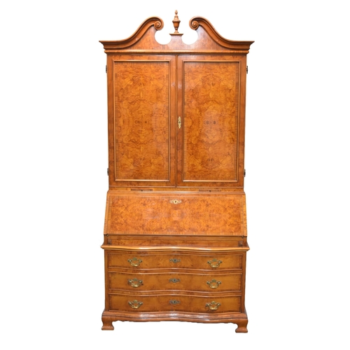 352 - A good reproduction walnut bureau cabinet The swan-neck pediment above twin panelled doors with inte... 