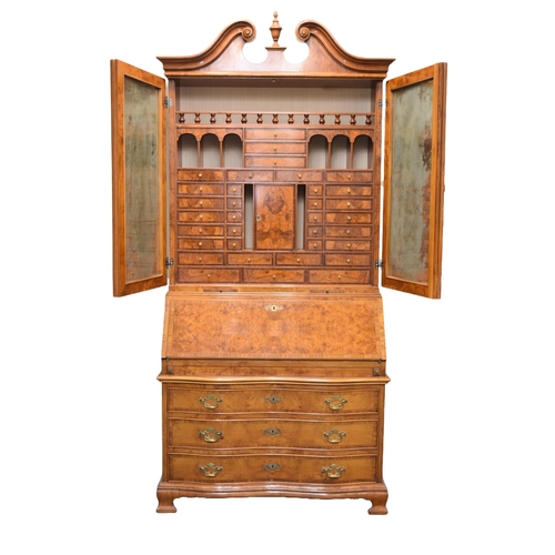 352 - A good reproduction walnut bureau cabinet The swan-neck pediment above twin panelled doors with inte... 