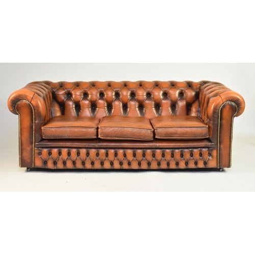 355 - A tan leather Chesterfield suite, 20th century Comprising a three-seat sofa and two armchairs Sofa 1... 