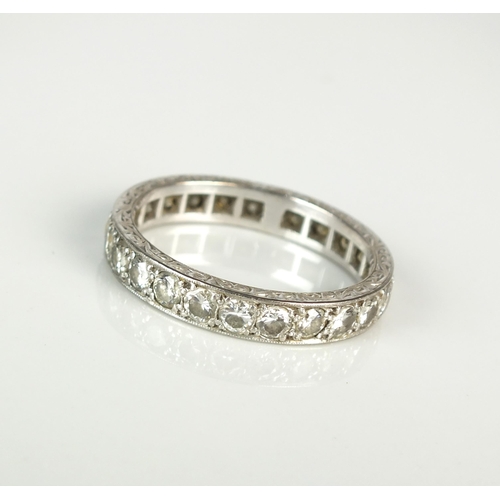 37 - A diamond eternity band, the brilliant cut diamonds claw set in white metal to bright cut engraved b... 