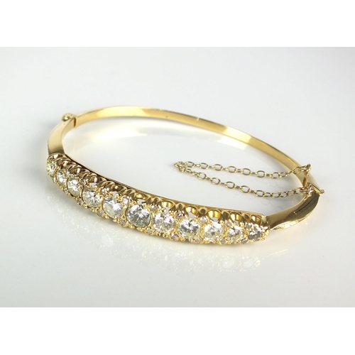 56 - A Victorian style diamond set hinged bangle, designed as a row of eleven graduated brilliant cut dia... 