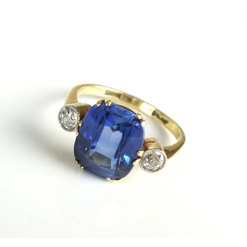 93 - A three stone synthetic sapphire and diamond ring, designed as a central cushion cut synthetic sapph... 