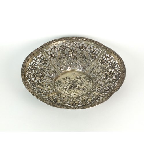 13 - A white metal decorative pierced bowl, the centre embossed with four cherubs amongst a landscape, al... 