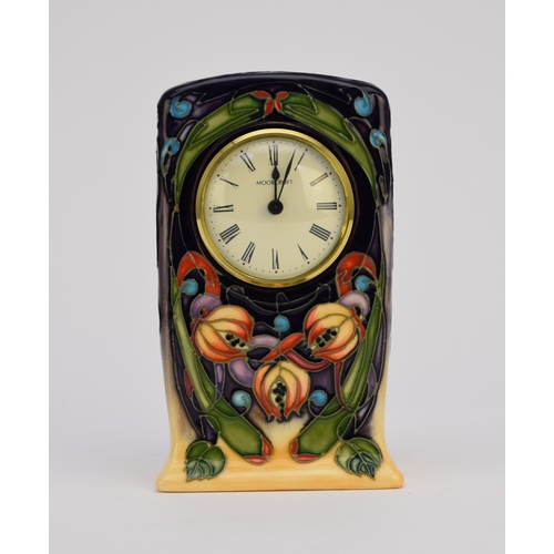 144 - A Moorcroft mantel timepiece, tubelined with flowers against a deep purple and pale orange ground, d... 