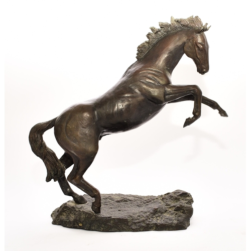 538 - A 20th century bronze figure of a horse The stallion modelled rearing up on its hind legs on a rocky... 