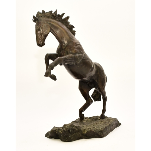 538 - A 20th century bronze figure of a horse The stallion modelled rearing up on its hind legs on a rocky... 