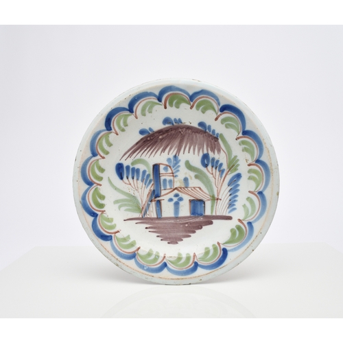 149 - An English delftware charger, 18th century, painted in polychrome with a building to the centre and ... 
