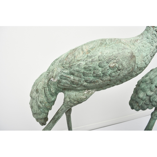 223 - A pair of bronze garden statues of crane birds, 20th century Both modelled standing, one with head r... 