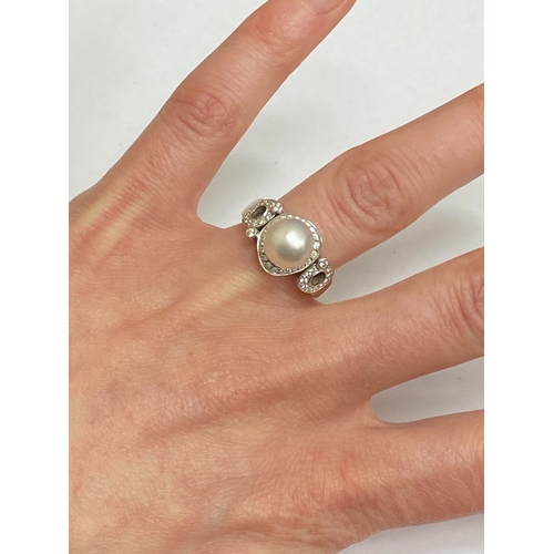26 - A De Beers 18ct white gold cultured pearl and diamond ring, designed as a central single cultured pe... 