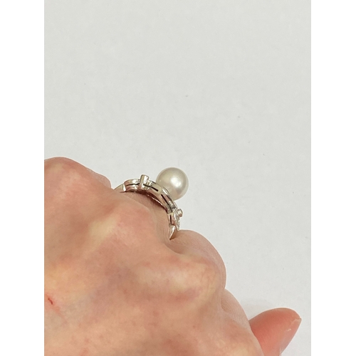 26 - A De Beers 18ct white gold cultured pearl and diamond ring, designed as a central single cultured pe... 