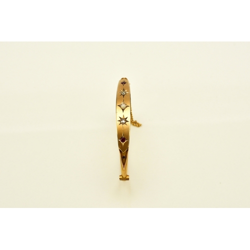 28 - An opal, diamond and red paste bangle, designed as a central round cabochon opal flanked to each sid... 