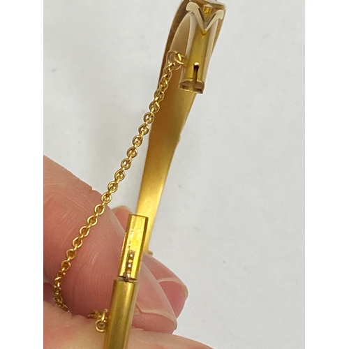 28 - An opal, diamond and red paste bangle, designed as a central round cabochon opal flanked to each sid... 