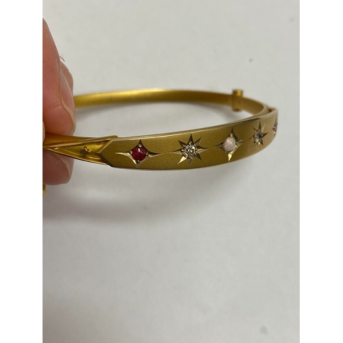 28 - An opal, diamond and red paste bangle, designed as a central round cabochon opal flanked to each sid... 