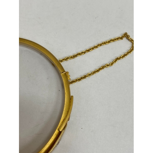 28 - An opal, diamond and red paste bangle, designed as a central round cabochon opal flanked to each sid... 