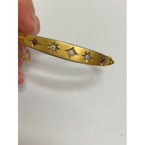 28 - An opal, diamond and red paste bangle, designed as a central round cabochon opal flanked to each sid... 