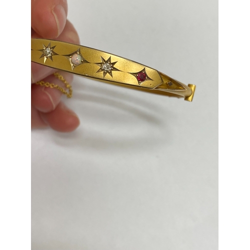 28 - An opal, diamond and red paste bangle, designed as a central round cabochon opal flanked to each sid... 