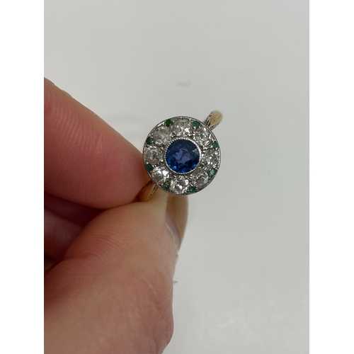 29 - An early-mid 20th century sapphire, diamond and emerald cluster ring, designed as a central round mi... 