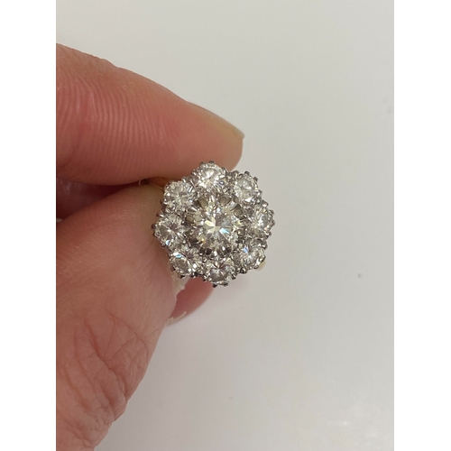 32 - An 18ct gold diamond floral cluster ring, designed as a central brilliant cut diamond claw set in wh... 