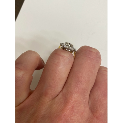 32 - An 18ct gold diamond floral cluster ring, designed as a central brilliant cut diamond claw set in wh... 