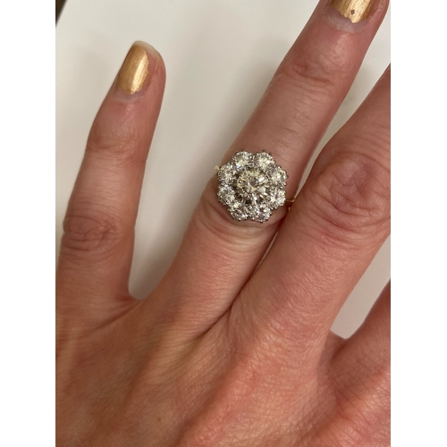 32 - An 18ct gold diamond floral cluster ring, designed as a central brilliant cut diamond claw set in wh... 