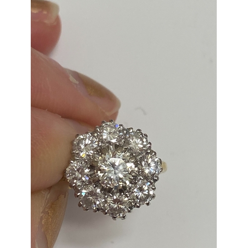 32 - An 18ct gold diamond floral cluster ring, designed as a central brilliant cut diamond claw set in wh... 