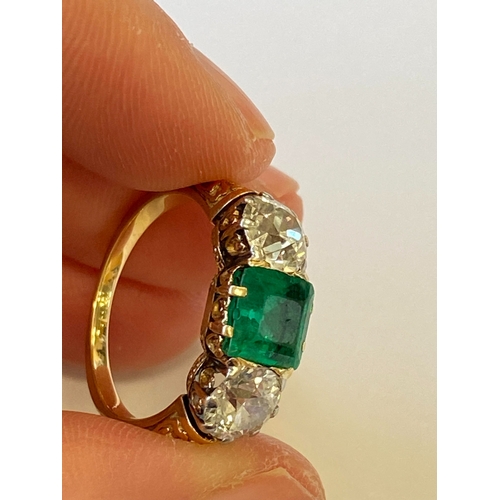 37 - A late 19th / early 20th century three stone emerald and diamond ring, designed as a central square ... 