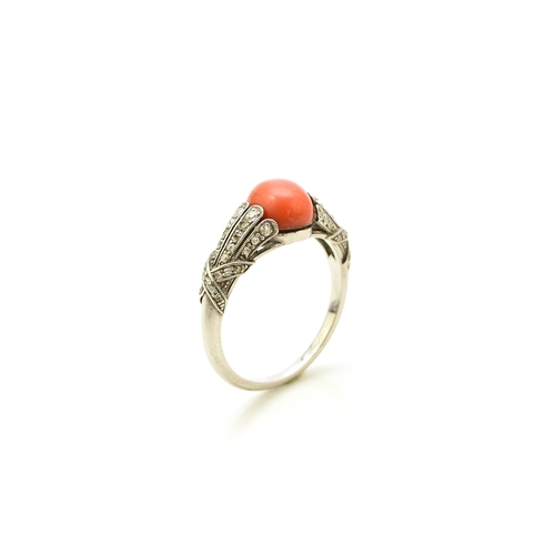 38 - A French Art Deco coral and diamond ring, designed as a single oval cabochon coral mounted within gr... 
