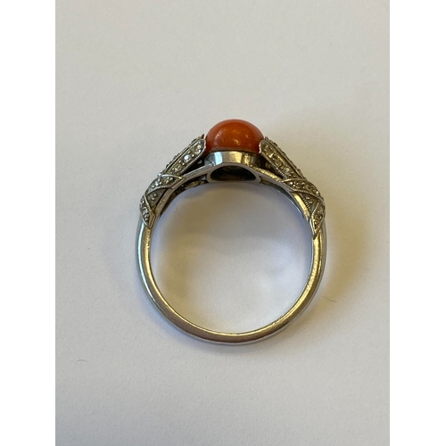 38 - A French Art Deco coral and diamond ring, designed as a single oval cabochon coral mounted within gr... 