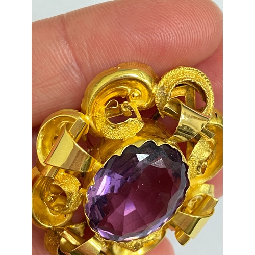 39 - A Victorian amethyst brooch, designed as a central oval mixed cut amethyst claw set within a yellow ... 