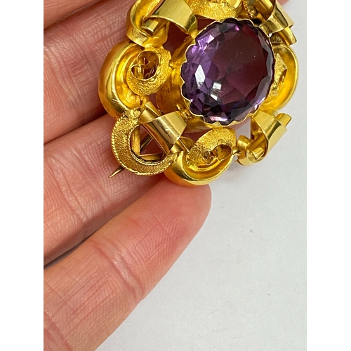 39 - A Victorian amethyst brooch, designed as a central oval mixed cut amethyst claw set within a yellow ... 