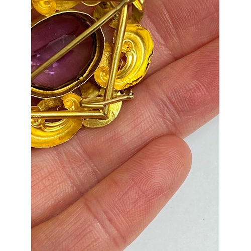 39 - A Victorian amethyst brooch, designed as a central oval mixed cut amethyst claw set within a yellow ... 