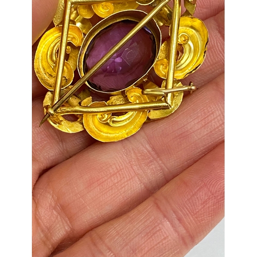 39 - A Victorian amethyst brooch, designed as a central oval mixed cut amethyst claw set within a yellow ... 