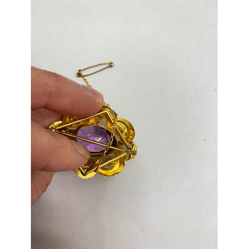 39 - A Victorian amethyst brooch, designed as a central oval mixed cut amethyst claw set within a yellow ... 