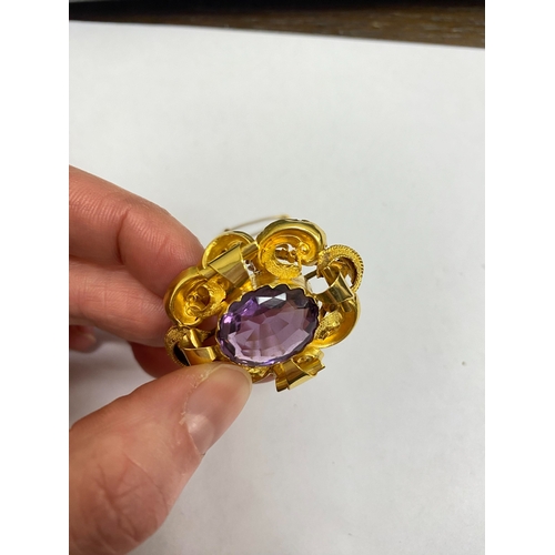 39 - A Victorian amethyst brooch, designed as a central oval mixed cut amethyst claw set within a yellow ... 