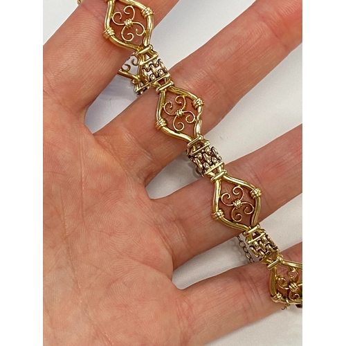 45 - A yellow metal decorative link bracelet, designed as seven openwork scroll links each interspersed w... 
