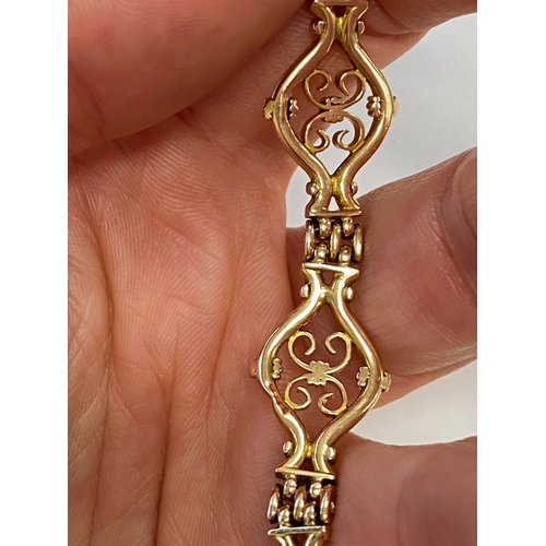 45 - A yellow metal decorative link bracelet, designed as seven openwork scroll links each interspersed w... 