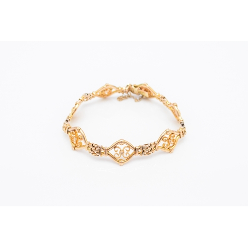 45 - A yellow metal decorative link bracelet, designed as seven openwork scroll links each interspersed w... 