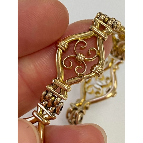 45 - A yellow metal decorative link bracelet, designed as seven openwork scroll links each interspersed w... 