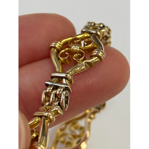 45 - A yellow metal decorative link bracelet, designed as seven openwork scroll links each interspersed w... 