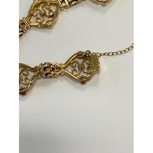 45 - A yellow metal decorative link bracelet, designed as seven openwork scroll links each interspersed w... 